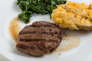 Tenderloin steak grilled to perfection with twice-baked potato and wilted spinach.