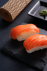 Salmon Nigiri Sushi on black slate stone with soy sauce and wasabi 