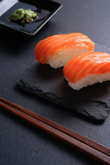 Salmon Nigiri Sushi on black slate stone with soy sauce and wasabi 
