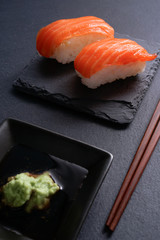 Salmon Nigiri Sushi on black slate stone with soy sauce and wasabi 
