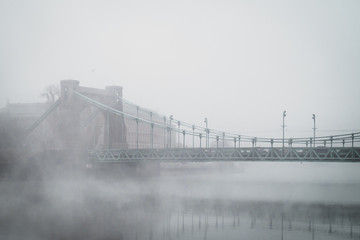 Old historical bridge during the misty, foggy day on the river.