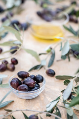 Olive oil in a glass bowl and freshly picked olives