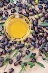 Olive oil in a glass bowl and freshly picked olives