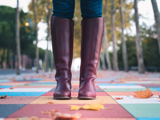 close-up plane of women's boots on a nice floor of colored squares with autumn leaves and a lot of blurring of the background