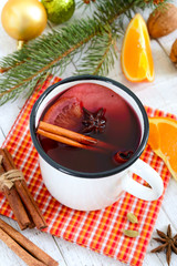 Hot mulled wine in a mug on a white wooden background. A traditional warming winter wine drink with aromatic spices.