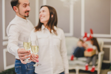 Fototapeta premium Toasting with champagne glasses against holiday lights and christmas tree.