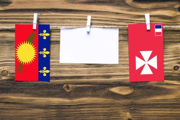Hanging flags of Guadeloupe and Wallis And Futuna attached to rope with clothes pins with copy...