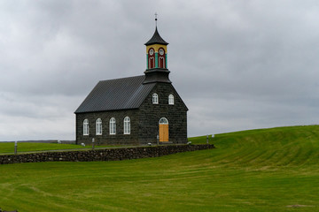 Black and colorful stone church on a hill