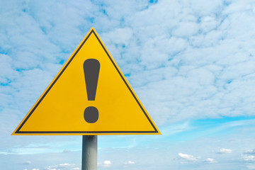 Hazard warning symbol. Attention road sign, yellow background, on sky background. Danger, be...