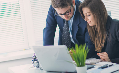 Young businessman discussing something with his colleague, and using a digital laptop together