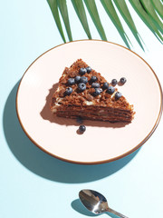A piece of blueberry pie with berries on a plate on a blue background. Top view.