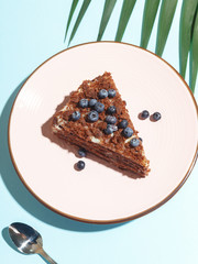 A piece of blueberry pie with berries on a plate on a blue background. Top view.