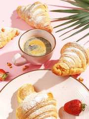 Appetizing croissants and a glass with a drink on a pink background.