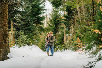 Couple loving in conifer forest on snowy day. Winter vacation