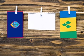 Hanging flags of Guam and Saint Vincent And The Grenadines attached to rope with clothes pins with...