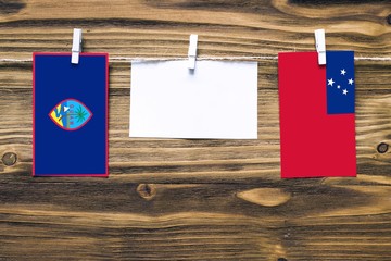 Hanging flags of Guam and Samoa attached to rope with clothes pins with copy space on white note...
