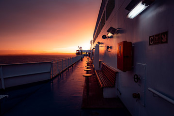 Deck of ferry sailing across the sea during last moments of a beautiful sunset with arriving land...