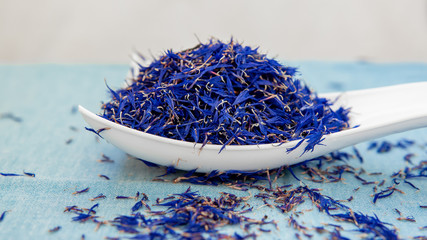 There are dry petals of cornflower blue, used as medicinal raw materials. A significant background of dried petals of cornflower. Natural light. Selective focus.