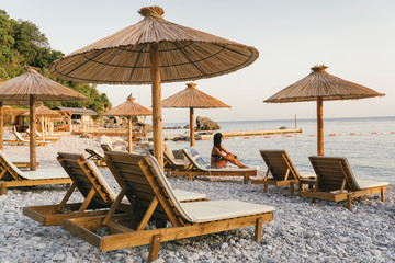 Pebble beach with hammocks and umbrellas at sunset in Jaz Beach, Montenegro.