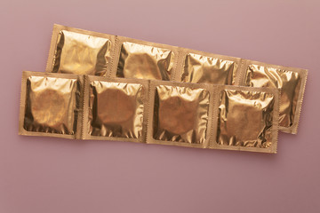 condoms in packaging isolated on a pink background, the concept of contraception and prevention of sexually transmitted diseases, stop HIV AIDS and hepatitis