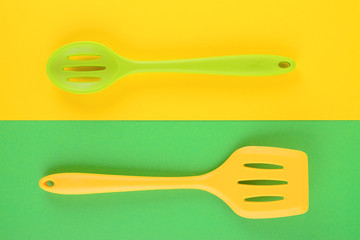 bright kitchen utensils on yellow and green background, creative idea