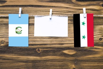 Hanging flags of Guatemala and Syria attached to rope with clothes pins with copy space on white...