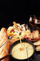 Gourmet Swiss fondue dinner on a winter evening with assorted cheeses on a board alongside a heated...