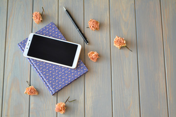 Blogger or frylance composition concept, smartphone, book and roses on wooden background