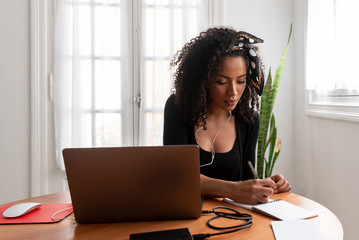 Shot of young latin woman working at home with laptop and documents
