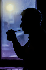 Old man with smoking pipe near  the night window, profile, dark silhouette
