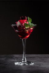 Dessert with Cherry Sauce, biscuits and mint in a martini glass on a black marble background