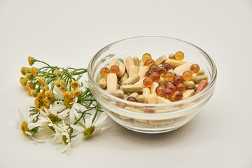 Alternative medicine.In a glass bowl are capsules and tablets, next to medicinal herbs.