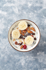 Bowl of granola with nuts, raisins and banana. Concept for a tasty and healthy meal. Rustic wooden background. Copy space. Top view. 