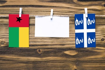 Hanging flags of Guinea Bissau and Martinique attached to rope with clothes pins with copy space on...