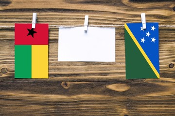 Hanging flags of Guinea Bissau and Solomon Islands attached to rope with clothes pins with copy...