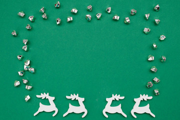 Fototapeta premium Christmas frame on dark green background with wooden handmade deers, decorations and copy space. Flat lay, top view, New Year banner mockup