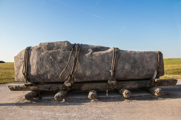 Standing stone horizontal on sledge with rollers  tied down with ropes like the stones at Stonehenge may have been moved