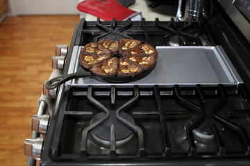 Chocolate brownies with walnuts baked in a cast iron wedge pan, resting on the stove top in a home...