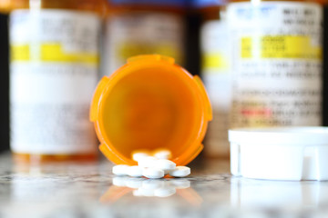 Precription bottles of pain pills on a granite countertop. 