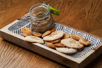 Homemade chicken liver pate in the jar on a wooden table, close-up.