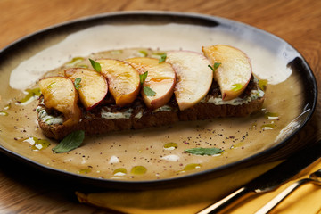 Traditional italian bruschetta with duck fillet, cream cheese and peach, close-up