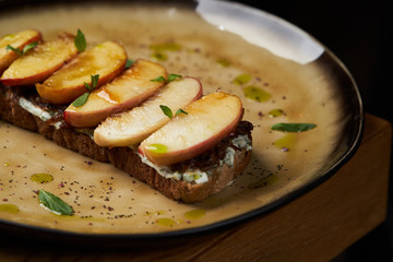 Traditional italian bruschetta with duck fillet, cream cheese and peach, close-up