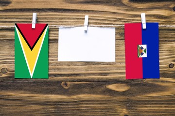 Hanging flags of Guyana and Haiti attached to rope with clothes pins with copy space on white note...