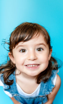 Portrait of cute little girl smiling very expressive on blue background