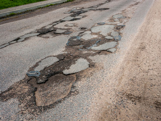 Old, broken asphalt with cracks and pits