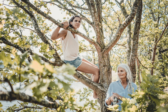 Mother and daughter having fun, climbing a tree