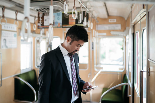 Young businessman using cell phone on a train
