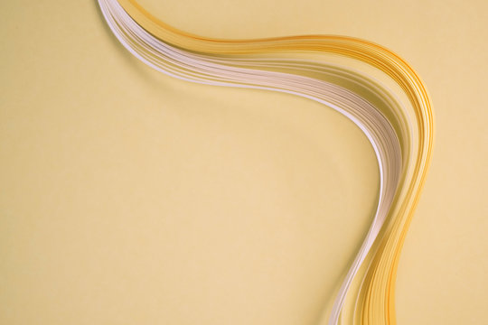 Close-up of curved quilling papers on beige background