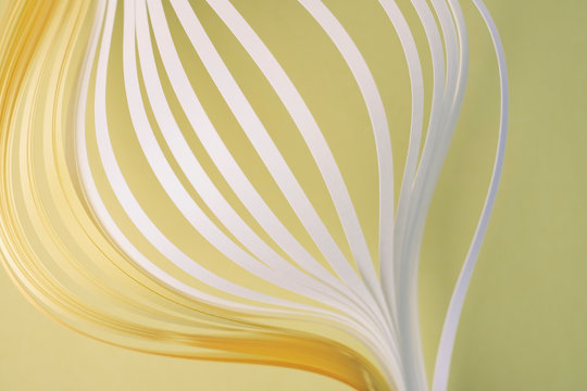 Close-up of white and yellow quilling papers on beige background