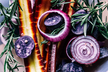 Autumn vegan food: purple onion rings, purple haze carrots, violet potatoes, rosemary